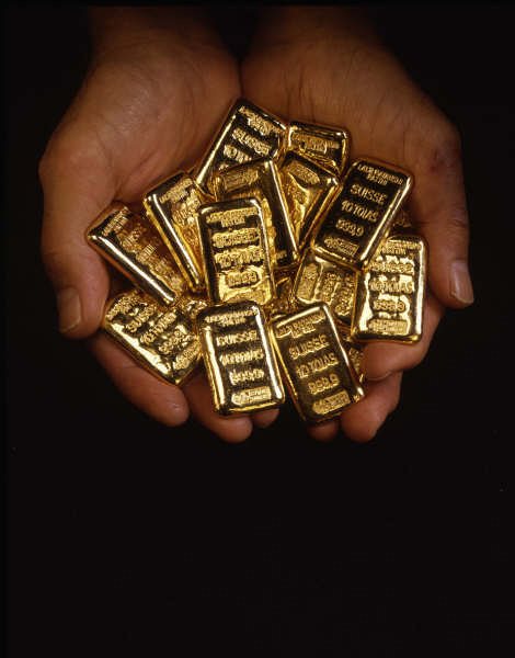 Gold bullion bars held in hands
